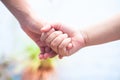 Female childÃ¢â¬â¢s hand holding the hand of elder male shot with a bokeh background and horizontal.